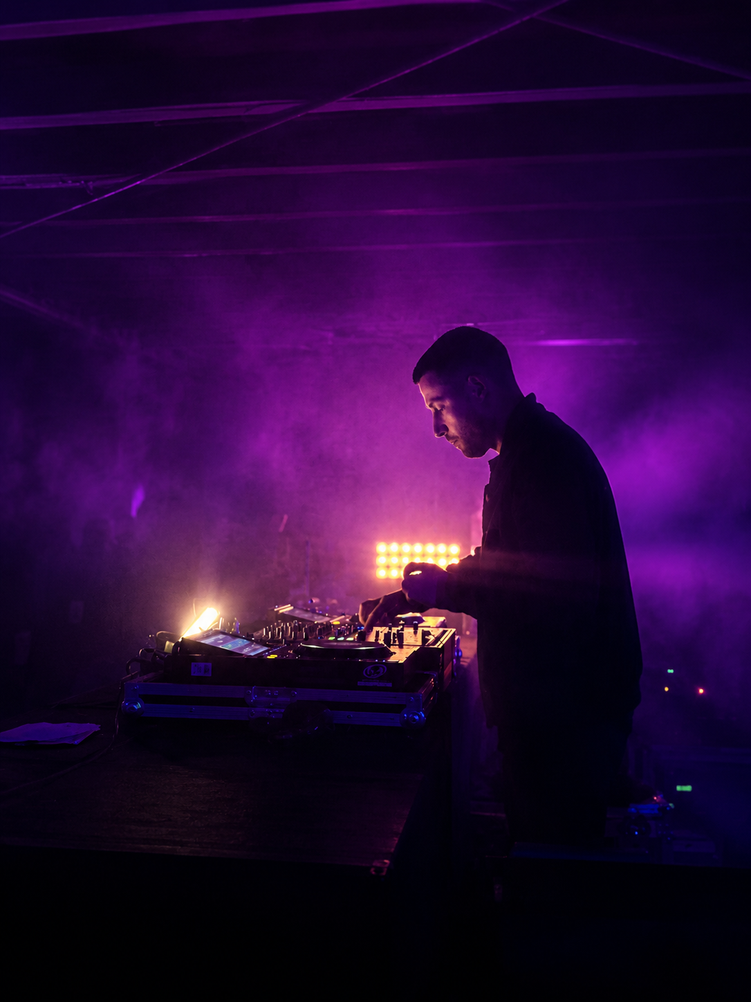 DJ am Pioneer-CDJ-Setup mit stimmungsvollem Licht